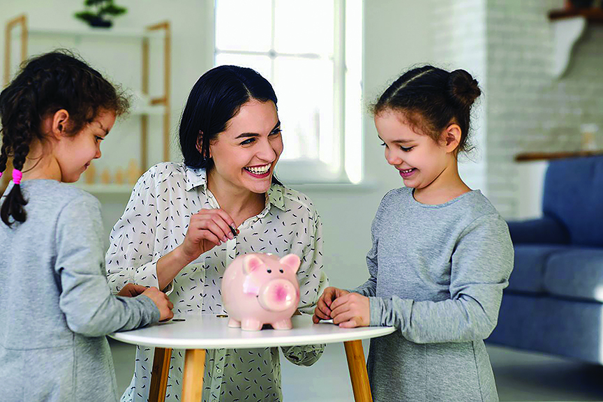 Two daughters watch as mom puts money in piggy bank