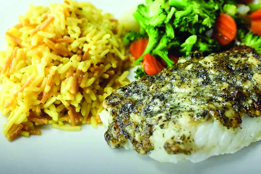 A plate with a serving of baked cod and sides of yellow rice and mixed vegetables