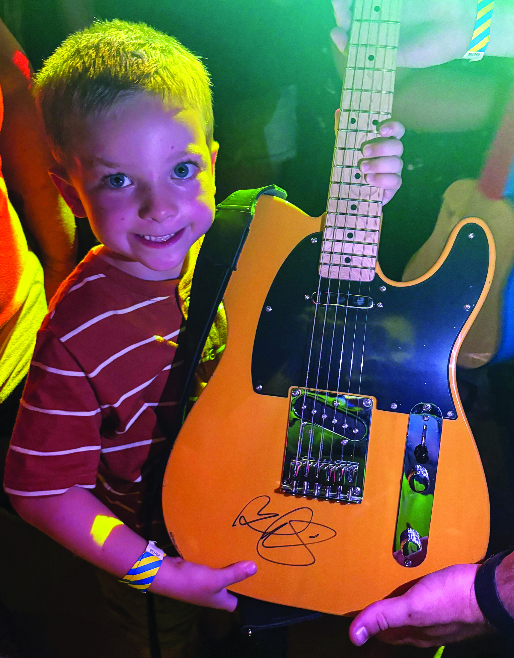 Young boy holds Brad Paisley's autographed guitar, a gift from the singer himself