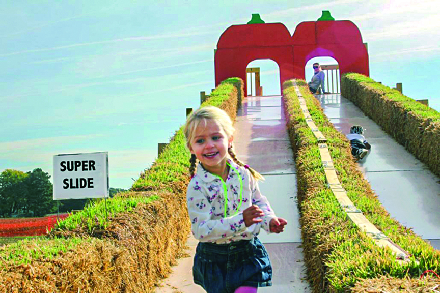 Girl runs after enjoying the super slide at Adkins Farm
