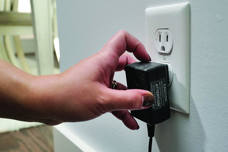 Hand unplugs power adapter from wall outlet