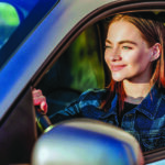 Young woman smiles behind the wheel of a car
