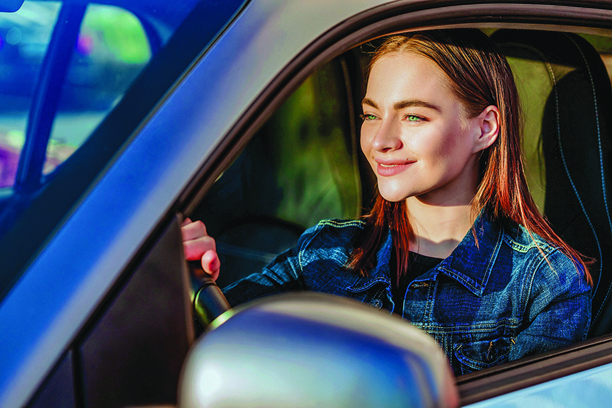 Young woman smiles behind the wheel of a car