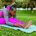 Woman stretches on yoga mat, showing a forward fold