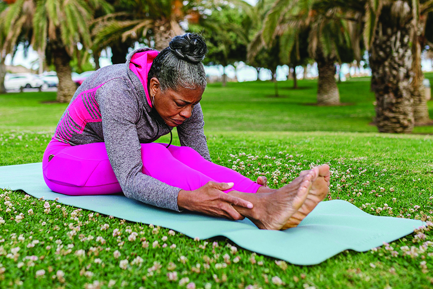 Woman stretches on yoga mat, showing a forward fold