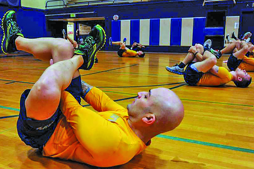 Men do figure four stretches in a gym