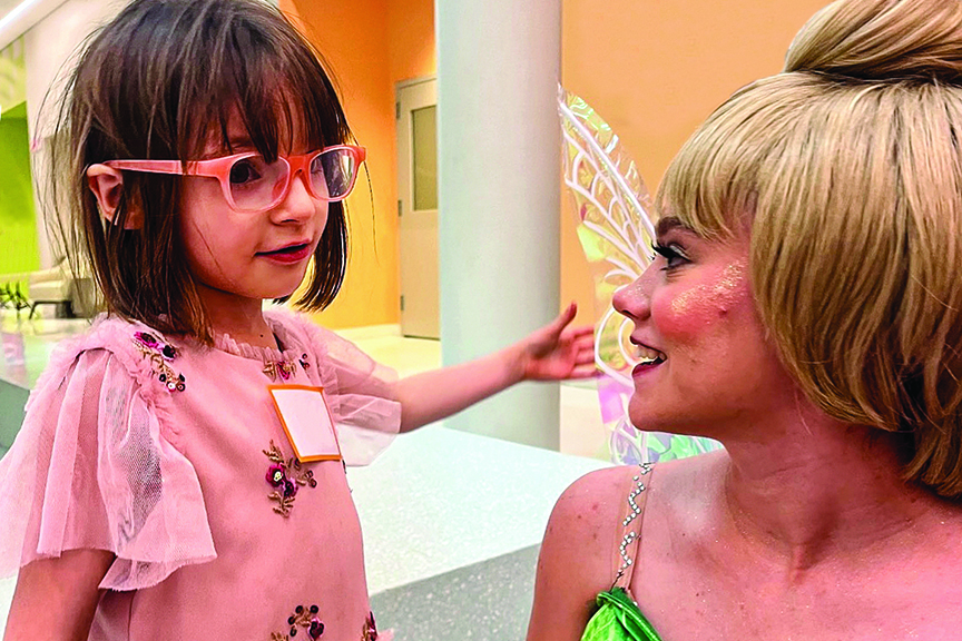 A young patient interacts with a woman dressed as a fairy.