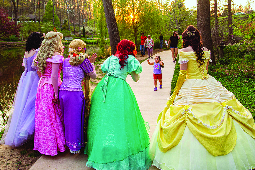 A young girl runs up to several princesses at scenic venue