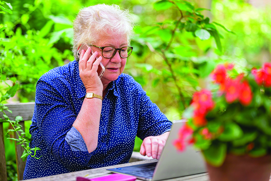 A woman sits outdoors speaking on the phone