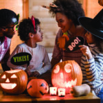 Family wearing halloween headwear gathers around jack o'lanterns