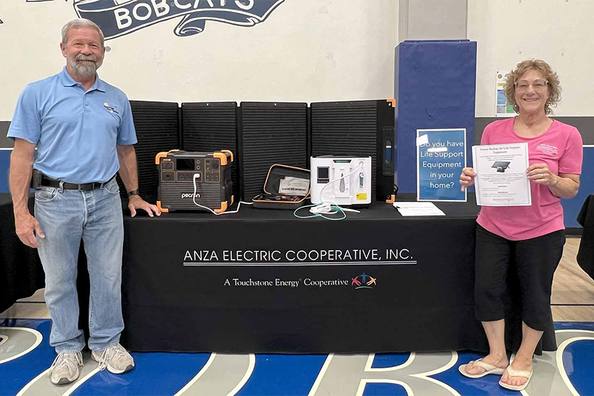 Anza Electric Cooperative General Manager Kevin Short and Member Service Rep Betsy Hansen next to solar-powered batteries distributed by the co-op to members requiring dialysis and oxygen concentrators.