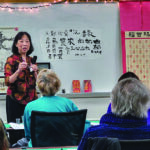 Margaret Wong stands in front of whiteboard as she teaches a class