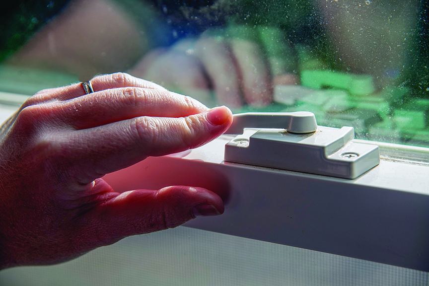 hand seen securing lock on interior window