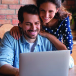 Man and woman look at laptop inside their home