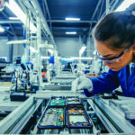 Woman wearing safety glasses assembles a small electronic device