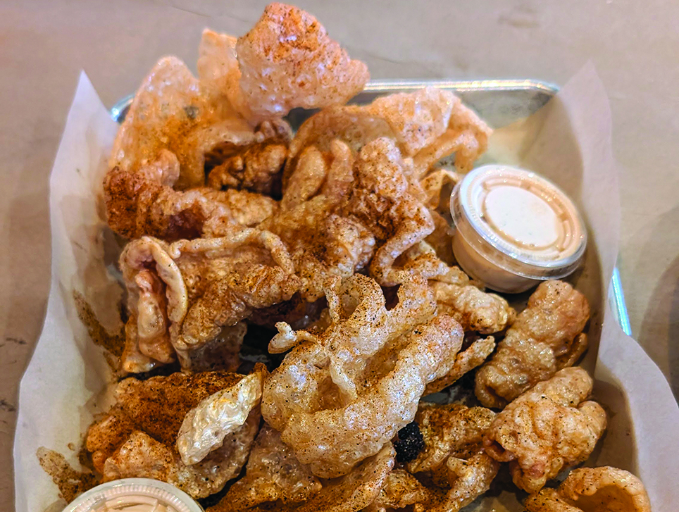 A platter of fresh-friend pork rinds with dipping sauce