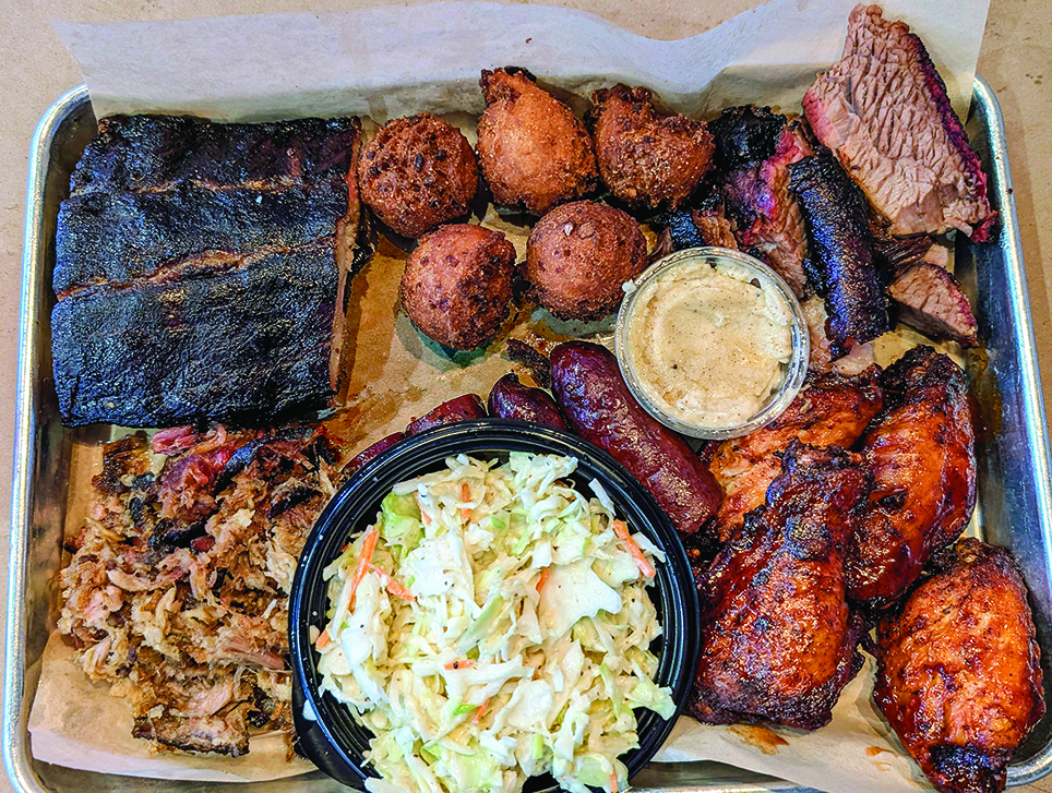 A platter containing various barbecued peats and cole slaw