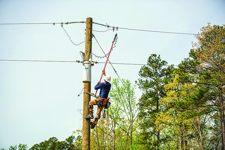 A student usesa hot stick in a training exercise that simulates working safely with energized equipment. 