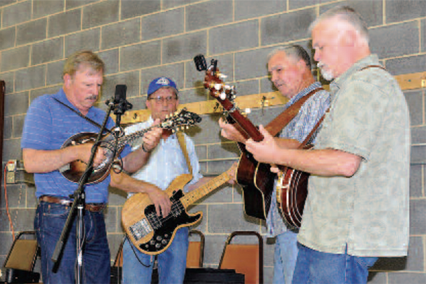 A group of four men, comprising guitarist and a banjo player, perform music