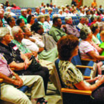 A seated crowd attends a meeting