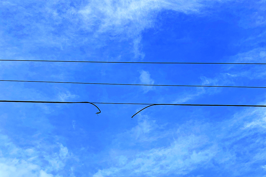 broken power line against blue sky