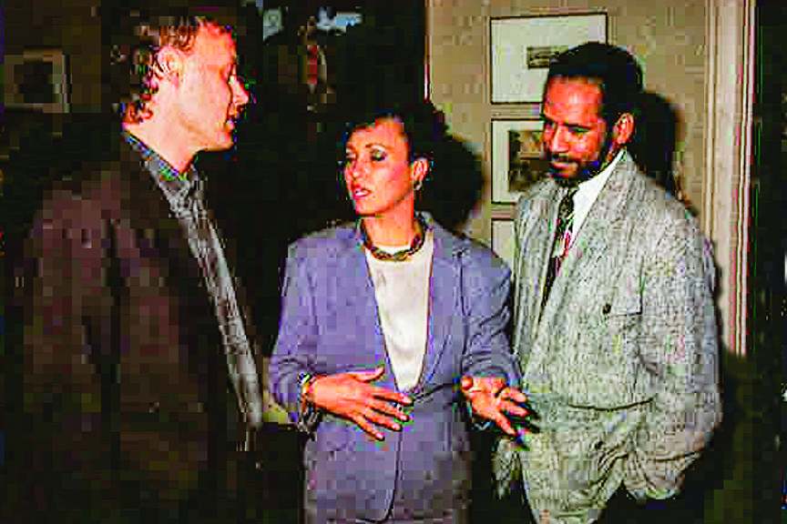 Musician Bruce Hornsby, in a dark blazer, talks to Daphne Maxwell Reif, who is gesturing in a purple blazer, as actor Tim Reid, in a gray sports jacket, looks on