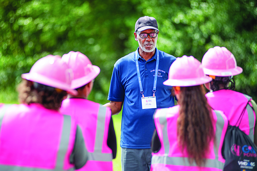 An instructor leads participants wearing pink helmets and vests during VMDAEC's Girl Power Camp, where high school girls explore careers in line work.