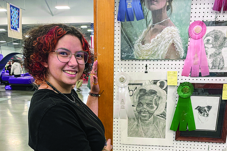 Student poses with art entries at the Virginia State Fair