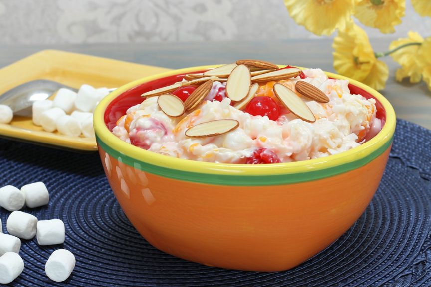orange bowl containing fruit salad with almonds on top 