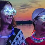 Women wearstar-shaped lit glasses at dusk