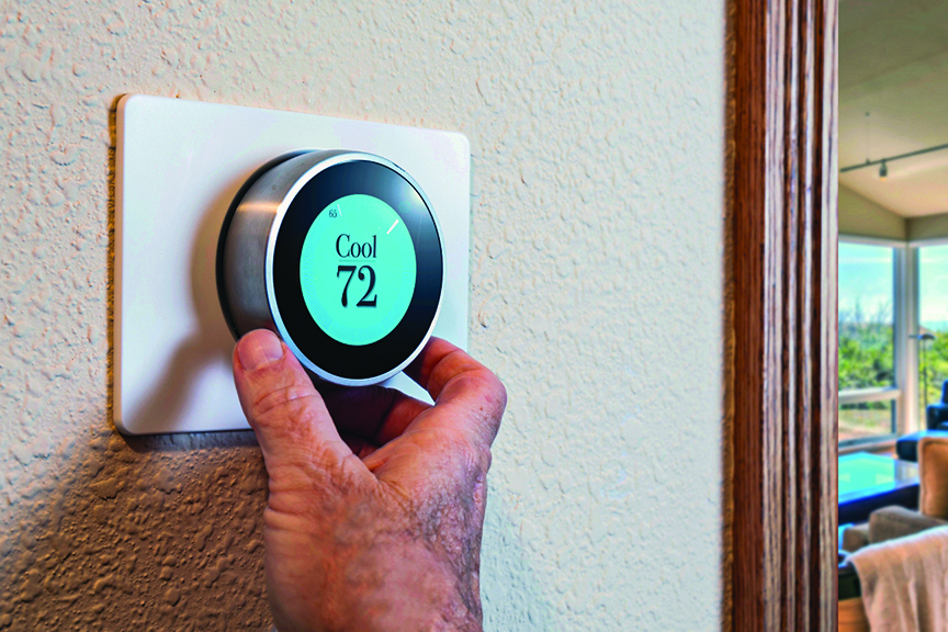 Man's hand adjusts smart thermostat, which is set to Cool at 72.