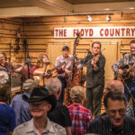 A live band performing bluegrass music on stage for a crowd at The Floyd Country Store.