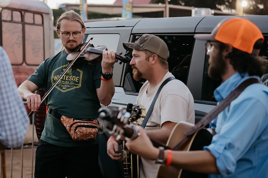 Three men play acoustic instruments outdoors