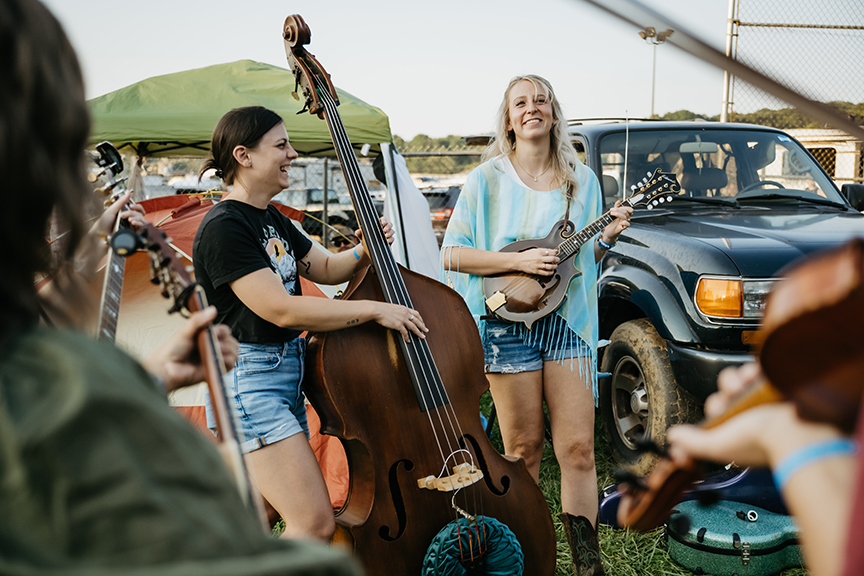 Two women laugh and jam together on acoustic instruments at the Old Fiddlers' Convention in Galax, Virginia.