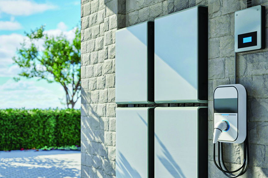 Wall-mounted home battery storage units and an EV charger on a stone exterior wall.