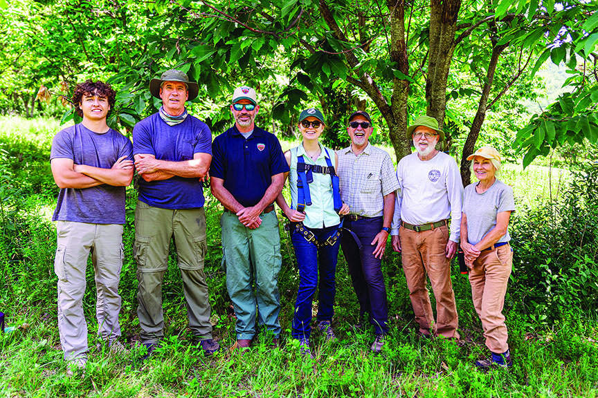 Group of seven individuals pose in a forest