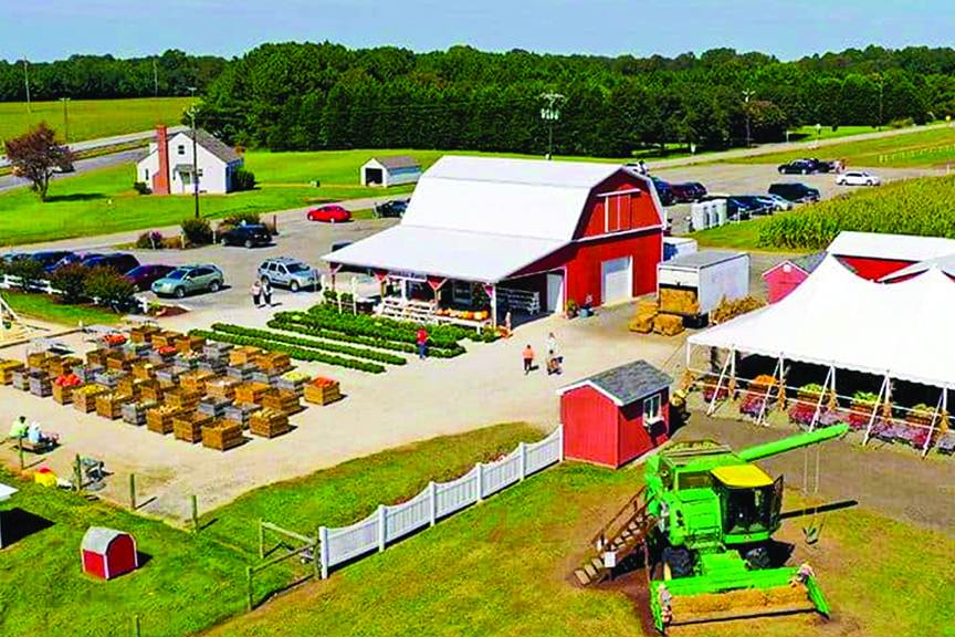 An aerial image of red barn, white tent, farm equipment, and lines of produce at Counsell Farms