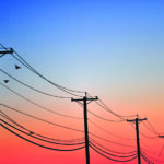 Silhouette of doves can be seen flying near power lines at dawn