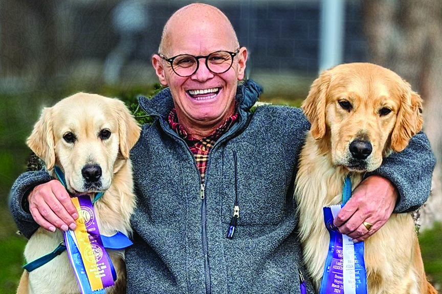 Michael Faulkner poses with a golden retriever on each side