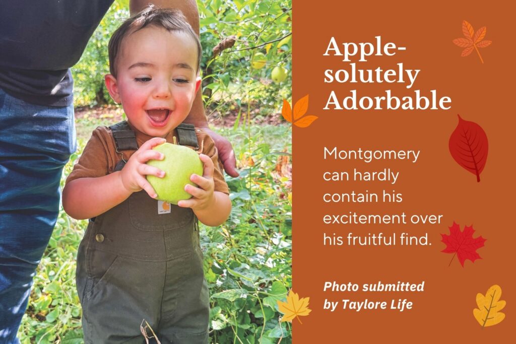 Photo of little boy smiling as he holds a green apple. Text: Apple-solutely Adorable. Montgomery can hardly contain his excitement over his fruitful find.