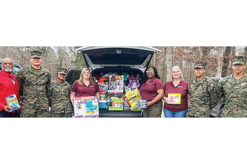 Prince George employees hold toys and pose for a photo alongside uniformed military personnel.