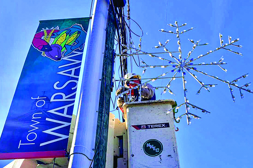 Lineworker in bucket truck helps install holiday lights and decor in the town of Warsaw.