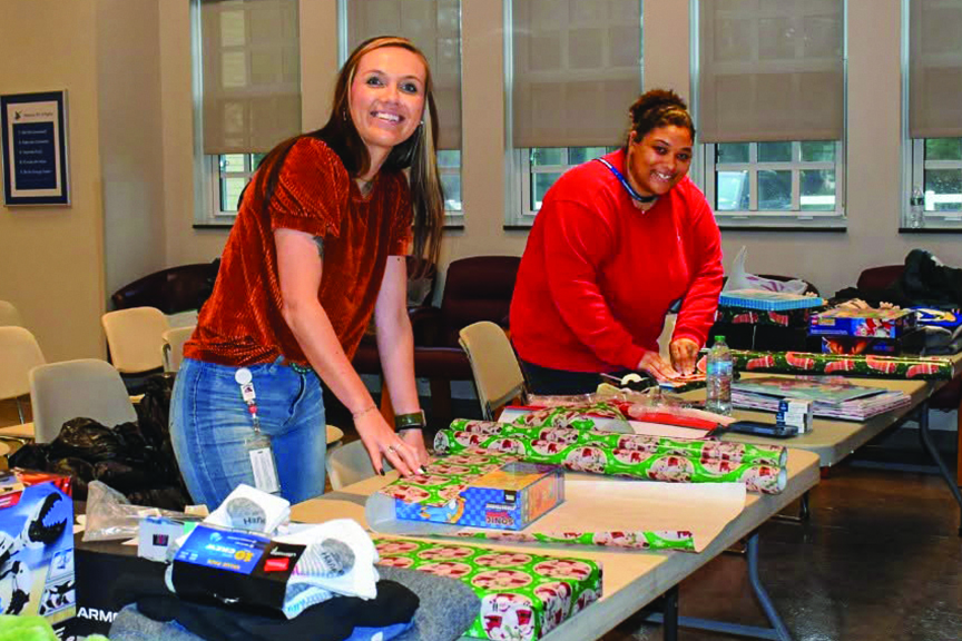 Two female Rappahannock Electric Cooperative employees wrap Christmas gifts for local families
